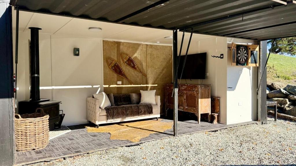 a screened in living room with a couch and a television at Grace & Rose in Gibbston