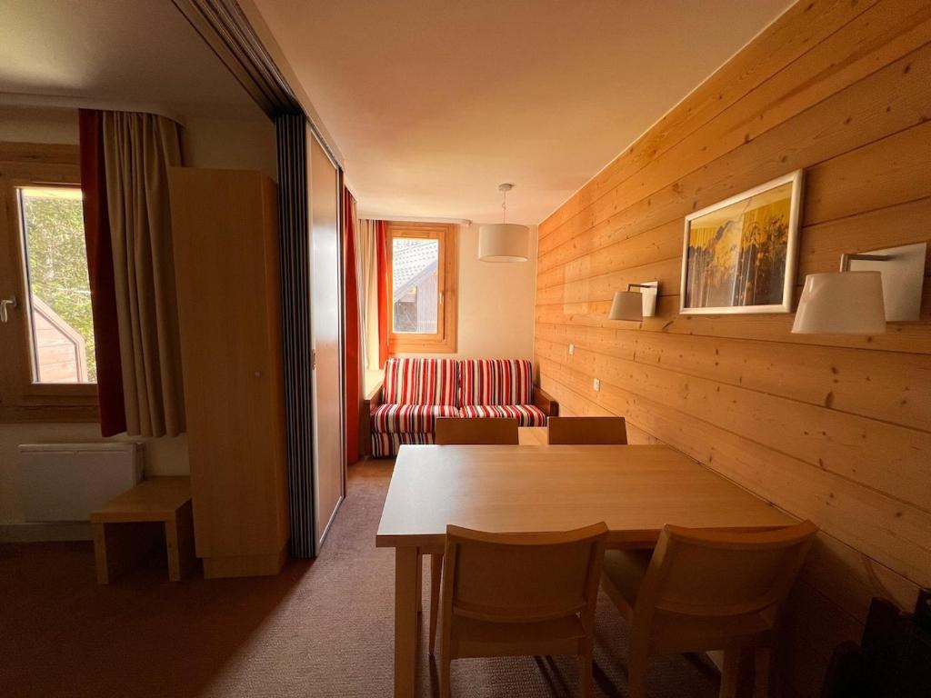 un salon avec une table et un canapé dans l'établissement Appartement piscine, sauna, skis, à La Plagne Tarentaise