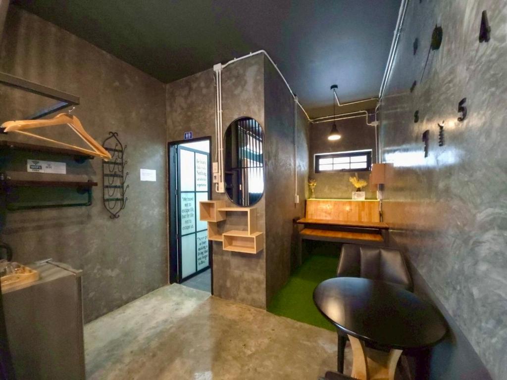 A compact industrial-style nook with a small round table, stools, a sink area, and hanging storage.