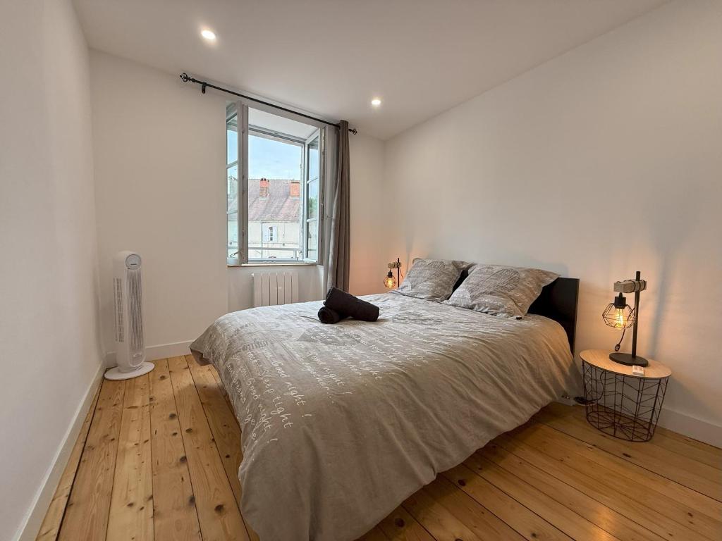 ein weißes Schlafzimmer mit einem großen Bett und einem Fenster in der Unterkunft Maison au cœur d Orgelet in Orgelet