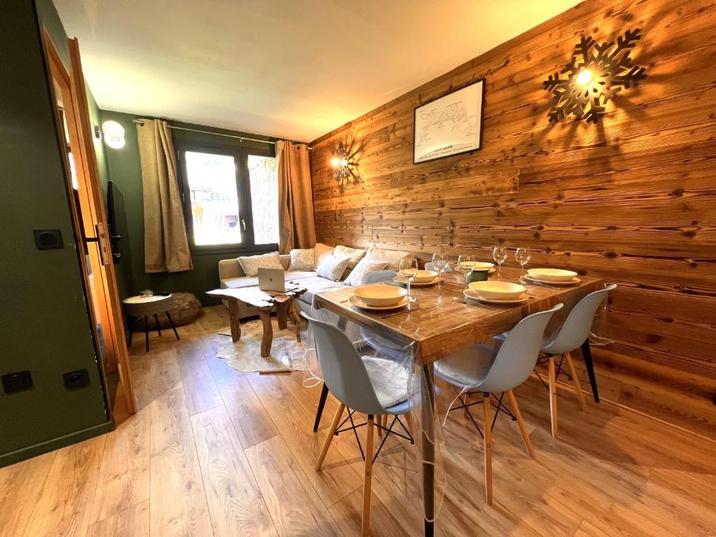 - une salle à manger avec un mur en bois, une table et des chaises dans l'établissement Esprit chalet, cosy et piscine, à La Plagne Tarentaise