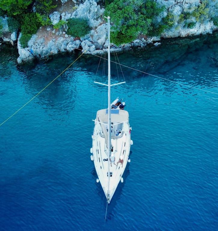 a white boat in the water next to a cliff at Nautical Nomads Yacht Charter in Tivat