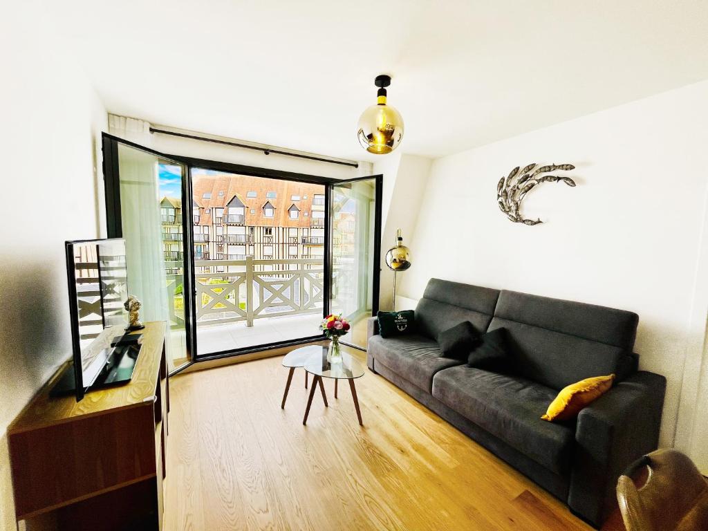 a living room with a black couch and a large window at Elégance & Confort, Proche place Morny, 3 Pièces, 2 Sdb, 2 WC, Balcon, Parking, Wifi ultra haut-débit, tout à pied in Deauville