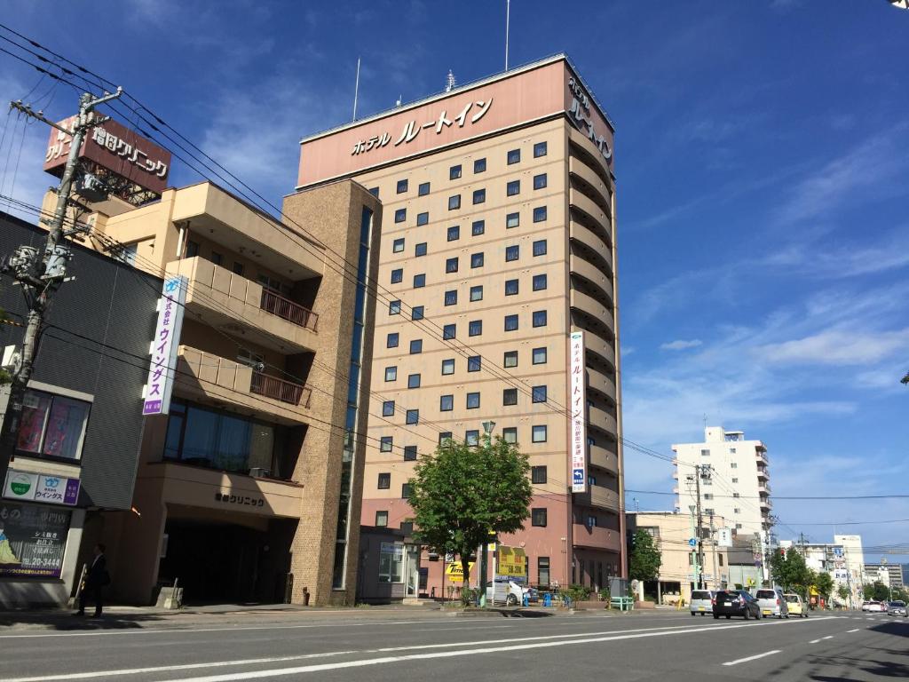 um edifício alto com uma placa no topo em Hotel Route-Inn Asahikawa Ekimae Ichijodori em Asahikawa