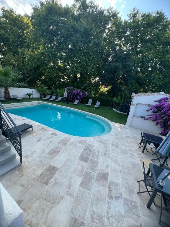 a swimming pool in a yard with chairs and trees at Les Acacias in Caveirac