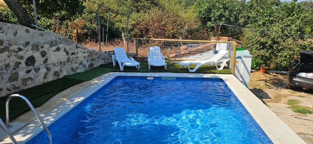 a swimming pool with two chairs and a table at Casa Rural Parajes del Chanza in Cortegana