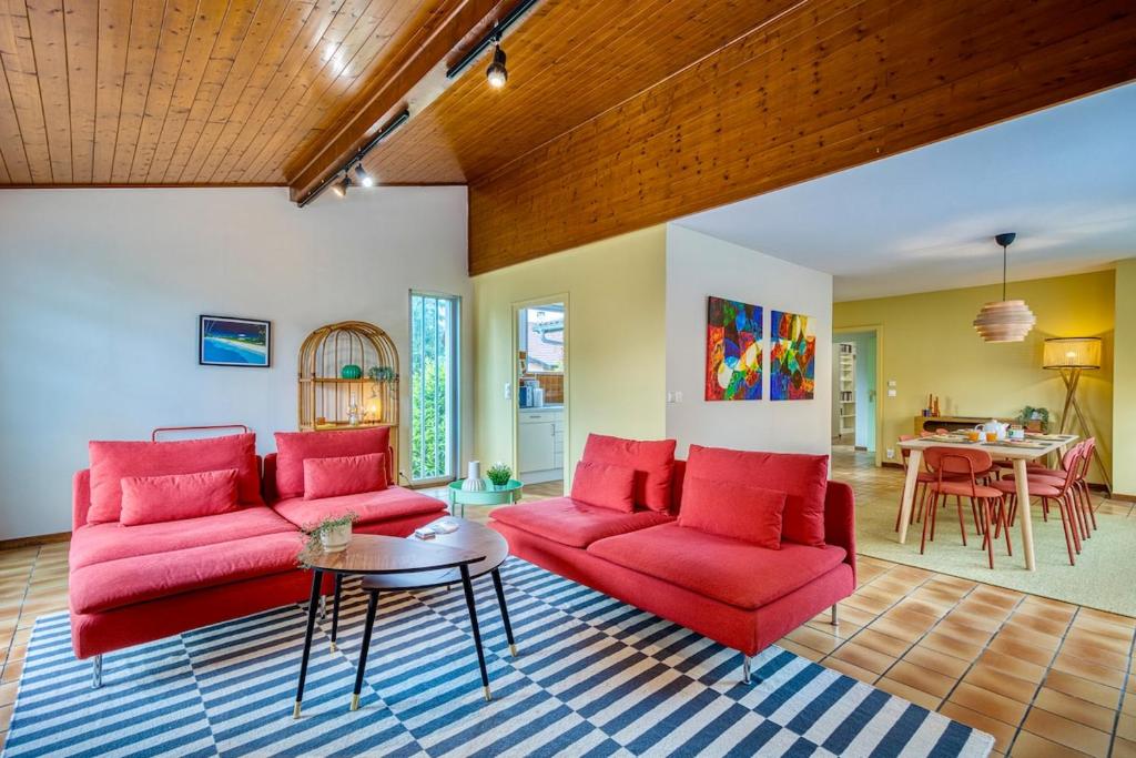 un salon avec des canapés rouges et une table dans l'établissement Alta House - Central Ferney and Family-Friendly, à Ferney-Voltaire