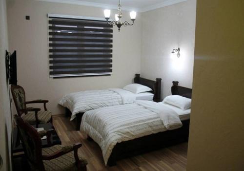 a bedroom with two beds and a window and a chair at Hotel Ulpiana, Ethno House in Gracanica