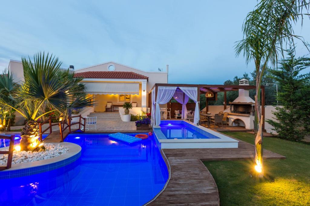 einen Hinterhof mit einem Pool und einem Haus in der Unterkunft Eva & Dimitrios Villas, By ThinkVilla in Panormos