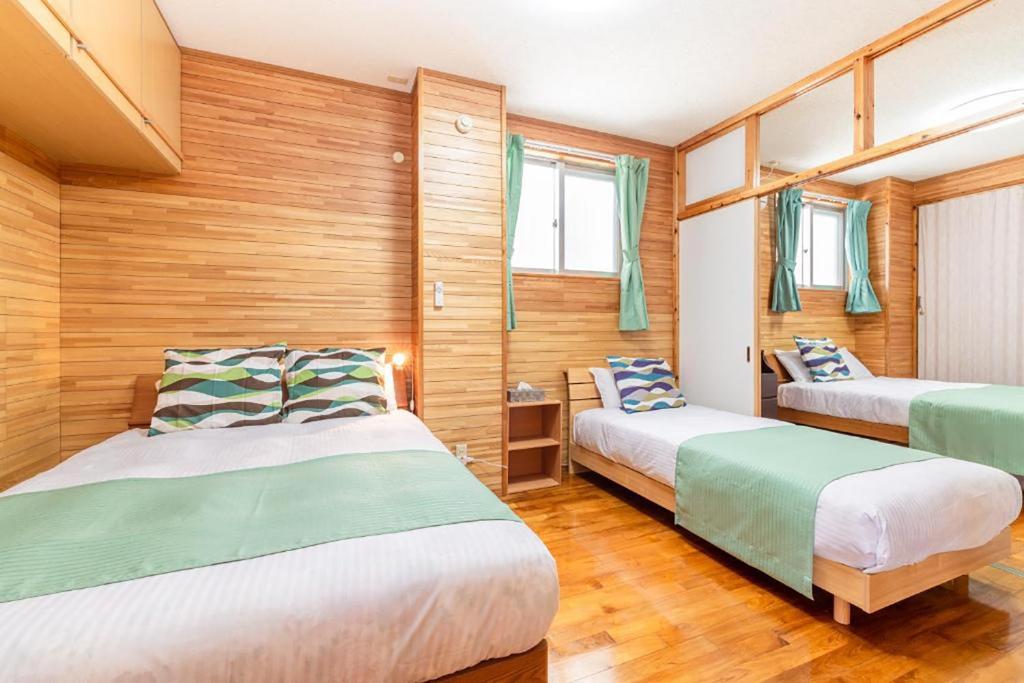 zwei Betten in einem Zimmer mit Holzwänden in der Unterkunft わったー家あぱらぎ館 in Ishigaki-jima