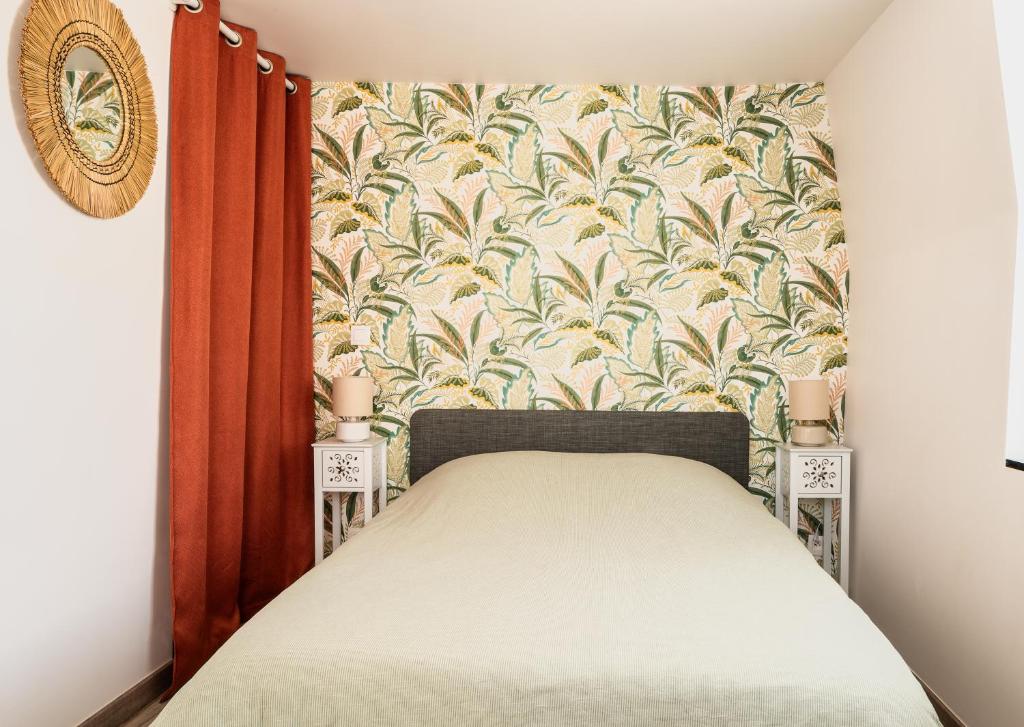 ein kleines Schlafzimmer mit einem Bett mit geblümter Tapete in der Unterkunft Villa Mona Studio Falaises quartier des Cordiers in Le Tréport