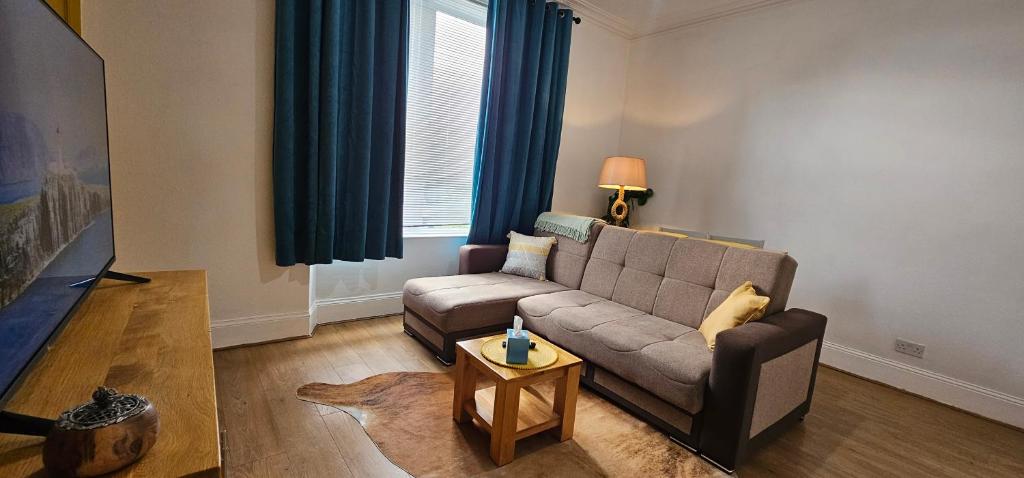 una sala de estar con un sofá y una mesa en Homestay, en Aberdeen