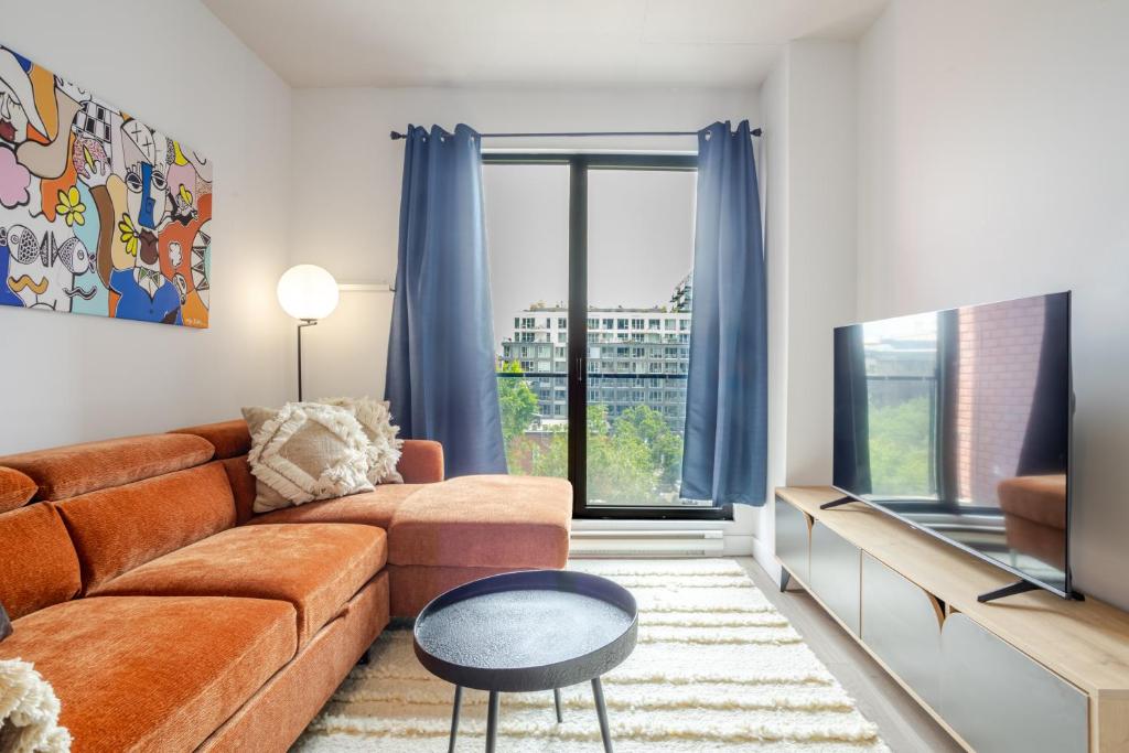 ein Wohnzimmer mit Sofa und Fernseher in der Unterkunft Modern Heritage Stay Upscale 2BR in Old Port in Montreal