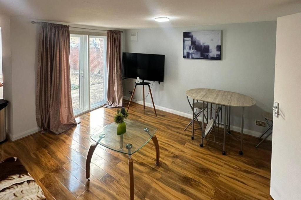 a living room with a table and a television at Cozy 1 Bed Apt Sleeps 4 with Garden Views in Hounslow