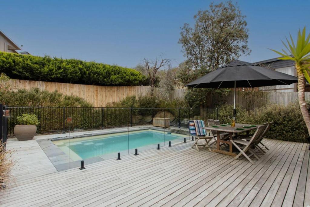 a patio with a table and an umbrella next to a pool at Mid Century on Eastview in Torquay