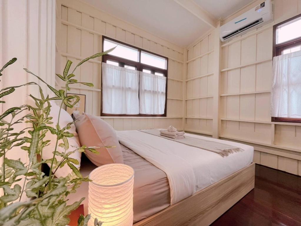 a bedroom with a bed in a room with windows at White & Green Guesthouse in Bangkok Yai