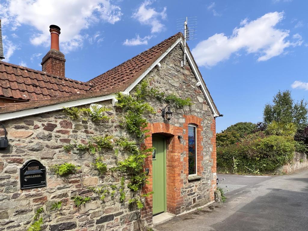 an old brick building with a green door at Tannery Cottage Porlock in Porlock
