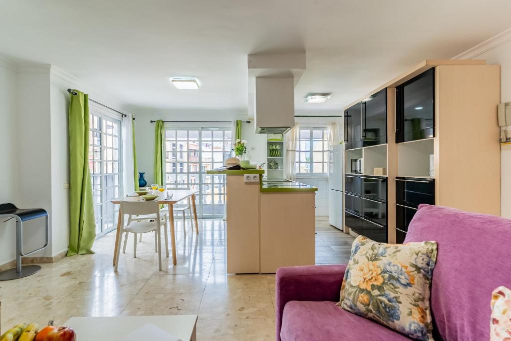 Il comprend une cuisine et un salon avec un canapé violet. dans l'établissement Encantador piso en centro de Puerto de la Cruz con gran terraza, à Puerto de la Cruz