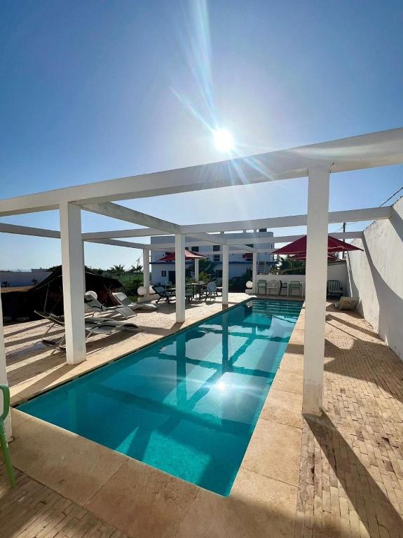 une grande piscine avec de l'eau bleue et des colonnes blanches dans l'établissement Riad Ocean Beach Douira, à Agadir