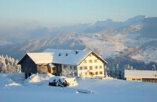 une maison au sommet d'une montagne enneigée dans l'établissement Haus Dreiländerblick, à Sulzberg