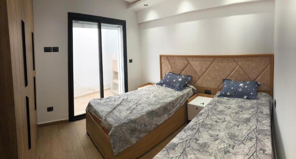 deux lits dans une petite pièce avec une fenêtre dans l'établissement Immobilier hammamet nord, à Hammamet