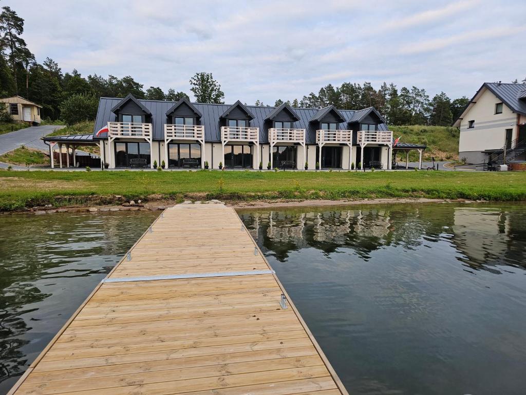 View from a dock towards cabins, reflecting in the calm lake water.