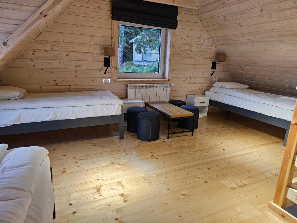 Attic room with two single beds, wooden walls, and a window view.