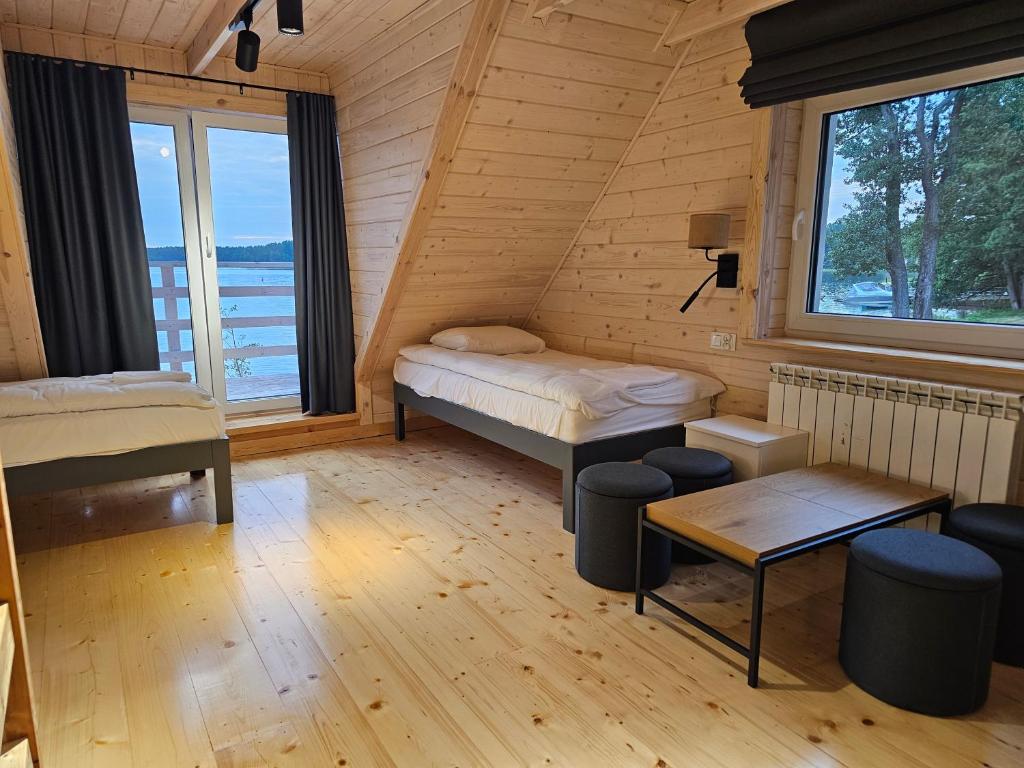 Wooden cabin interior with twin beds, a table, and a view of the lake.