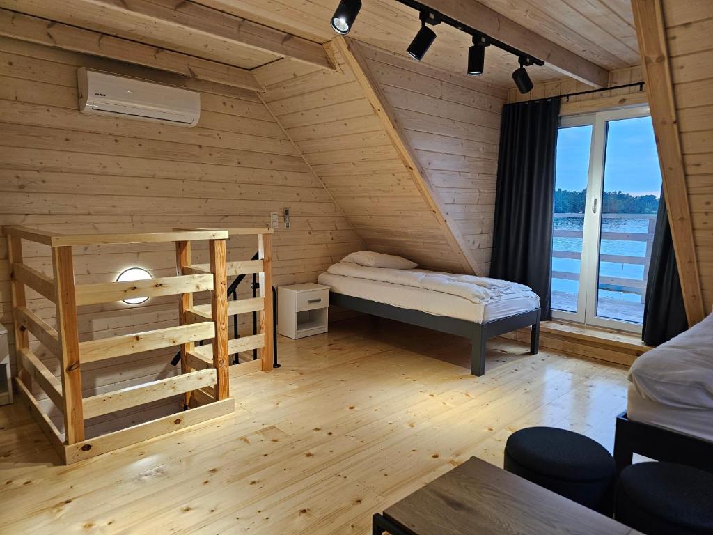 Attic room with bed, wooden interior, and balcony view of lake.