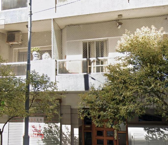 a white building with a balcony with two people on it at Studio Arena y Sol - MDQ Centro in Mar del Plata