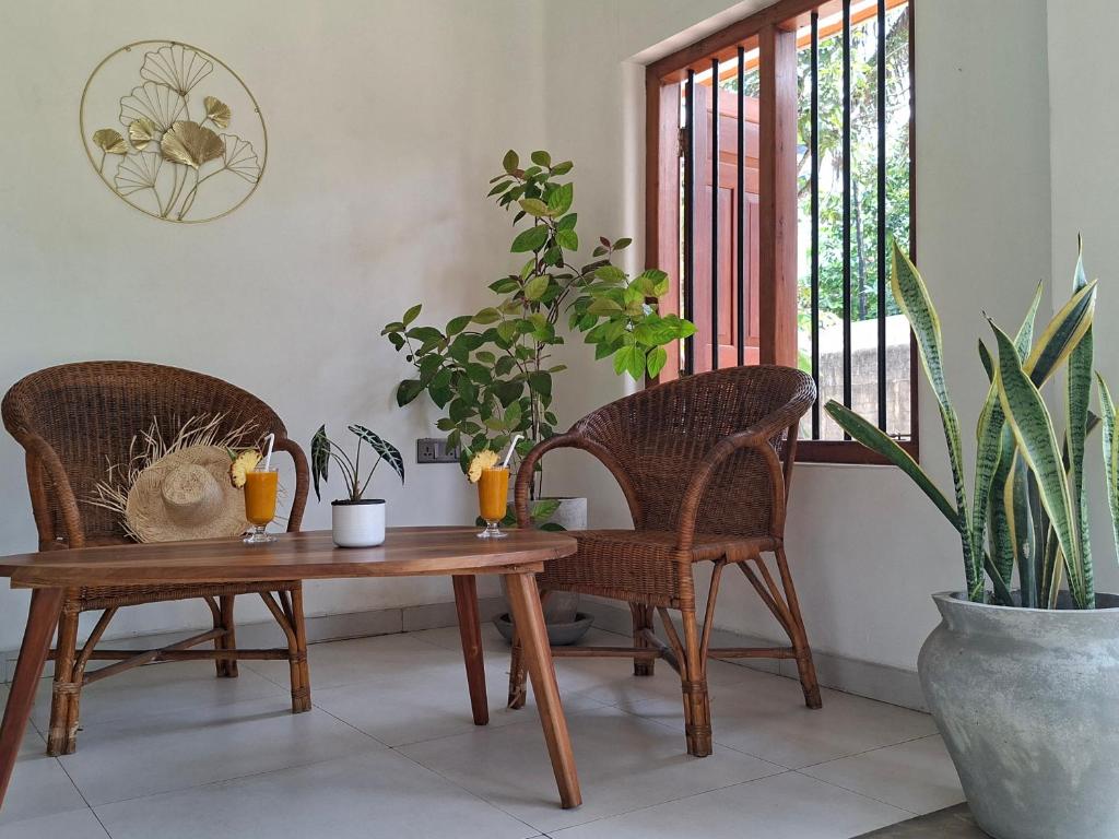 a room with two chairs and a table with plants at Naolina Beach Villa in Weligama