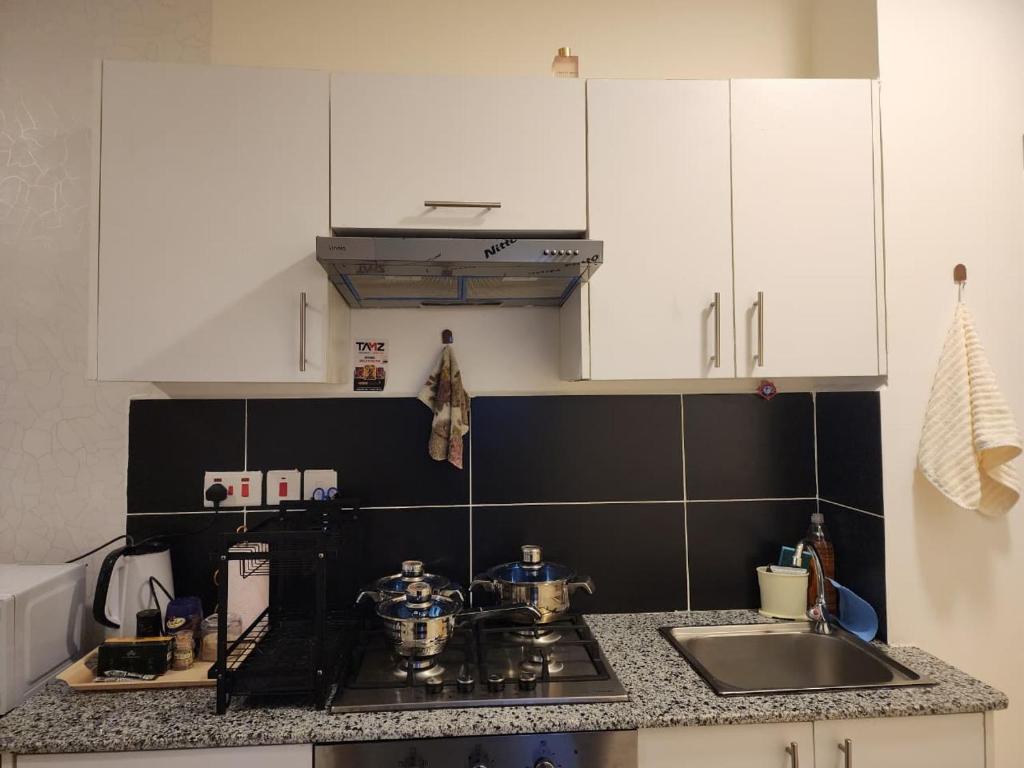 a kitchen with white cabinets and a stove and a sink at Mayaloft studio near JKIA and SGR in Nairobi