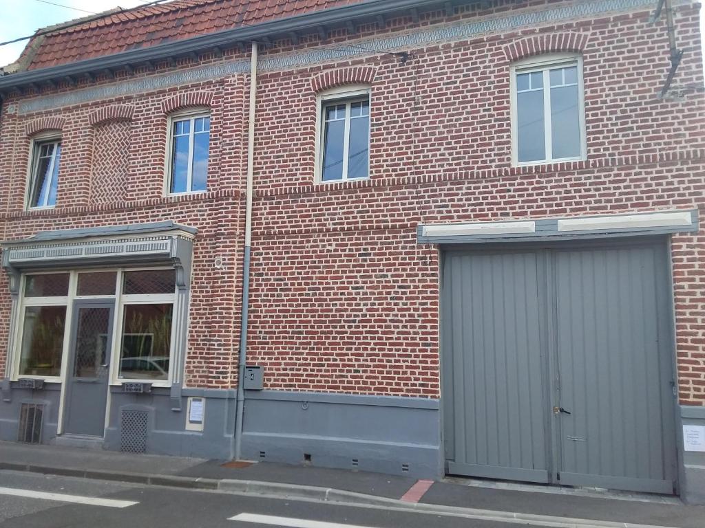 a brick building with two garage doors on a street at Chambre discrète 2 à 3 pers in Camphin-en-Carembault