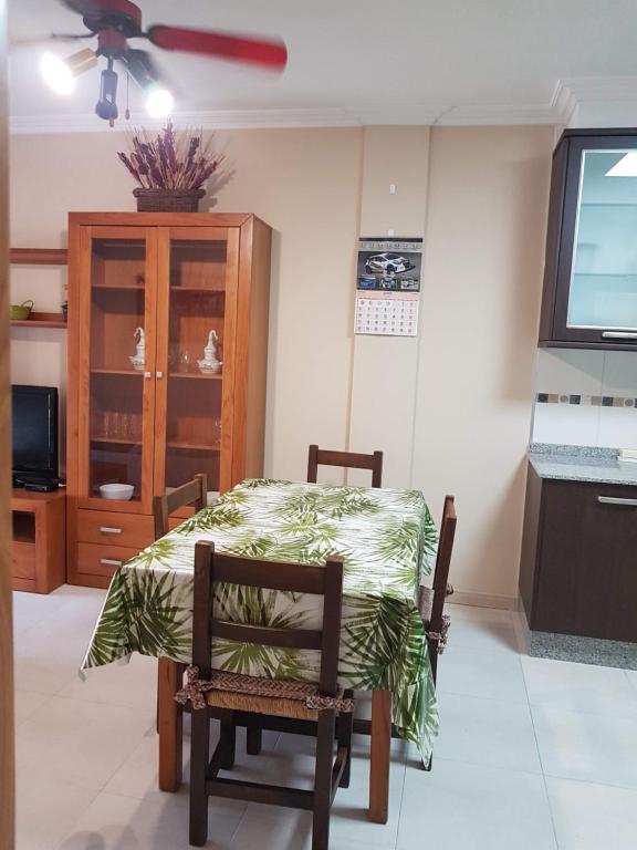 a room with a table and a chair and a tv at Piso Salón Paraíso in Bueu