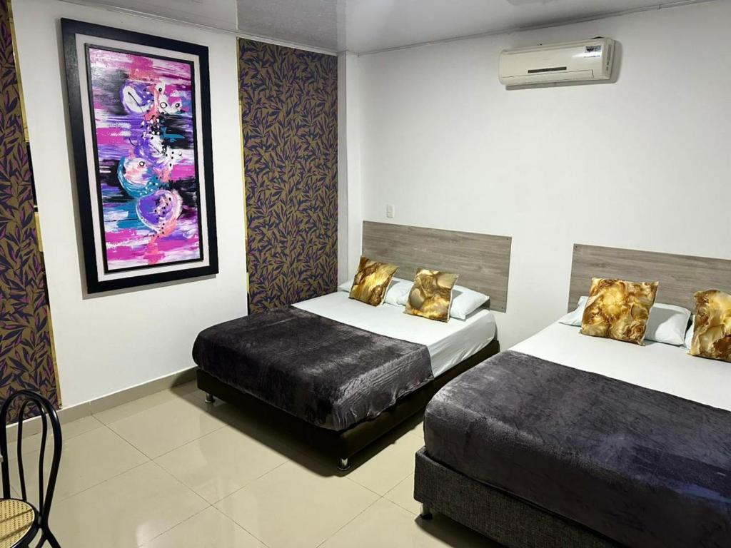 a hotel room with two beds and a painting on the wall at Brisas Centro Historico in Santa Marta