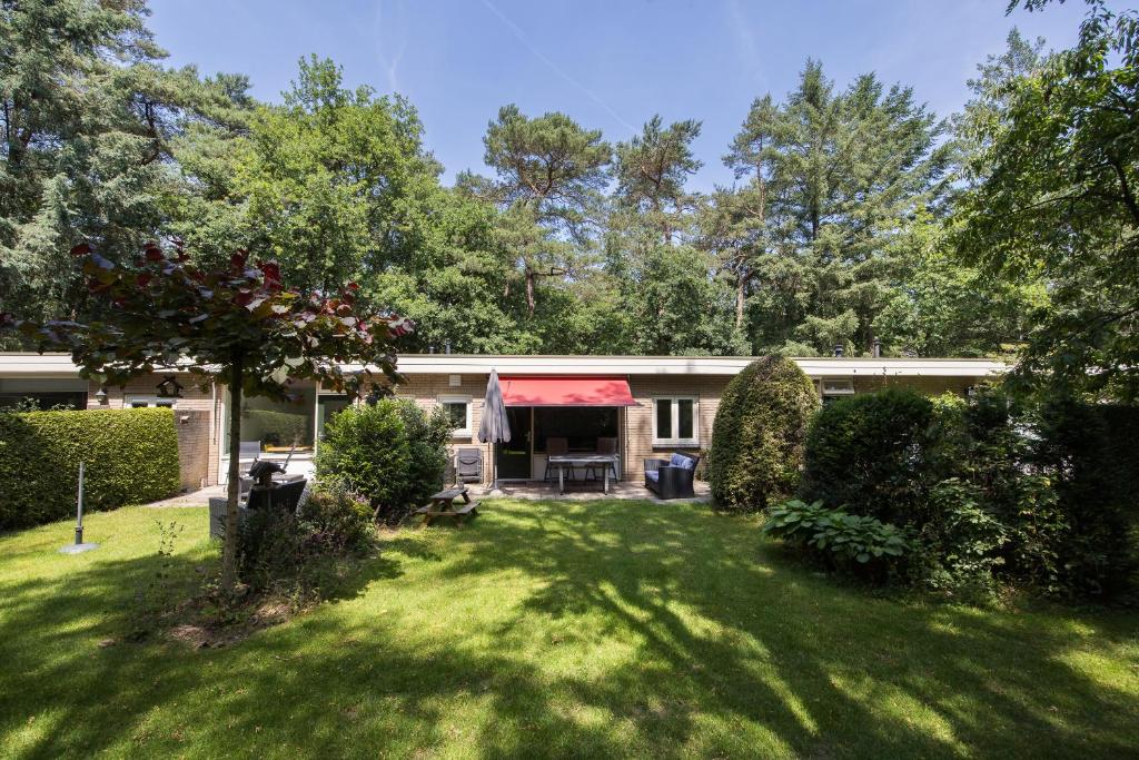a house with a red awning in a yard at Veluwe Nature Home - 2-4 persons in Otterlo