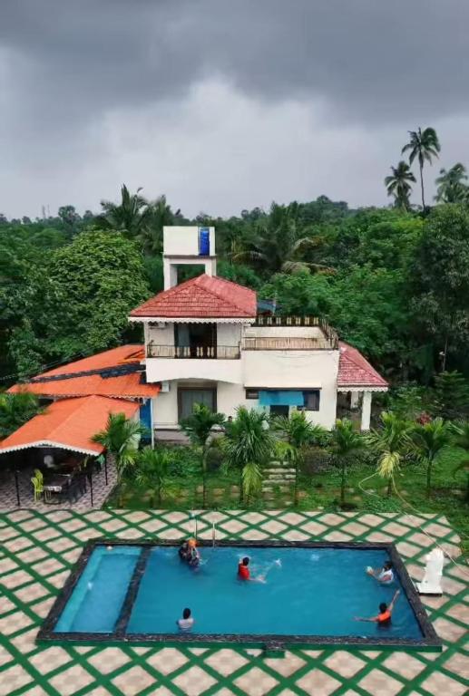a building with a swimming pool in front of a house at Vana Serene Villa in Ambepur