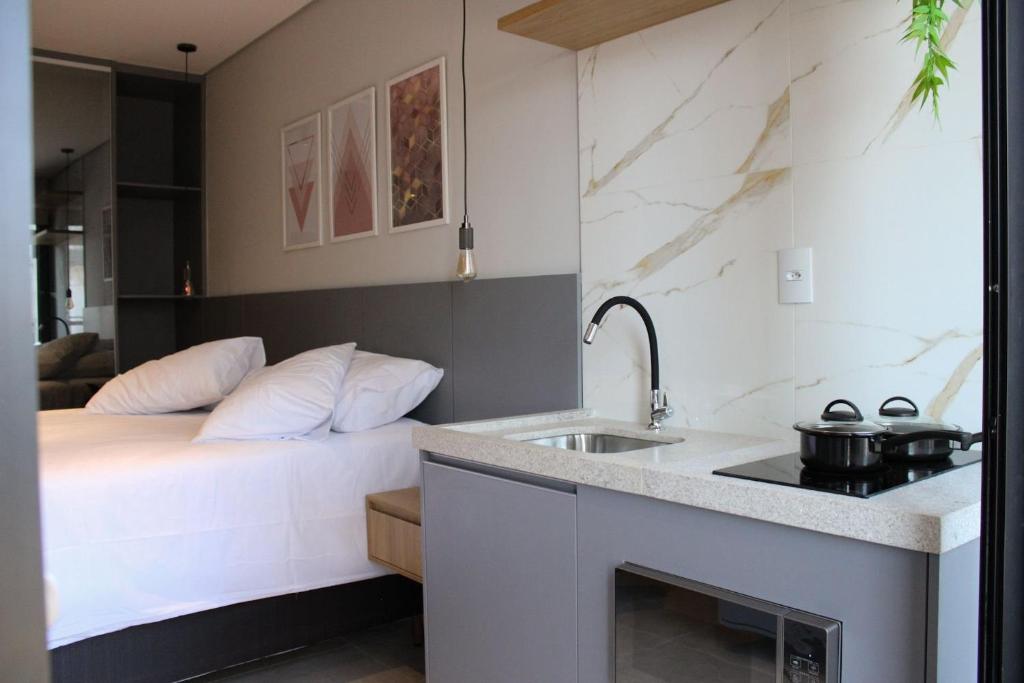 a bedroom with a bed and a sink and a kitchen at LOFT 190. Hospedagem Inteligente. Campo Belo, Minas Gerais, Brasil. in Campo Belo