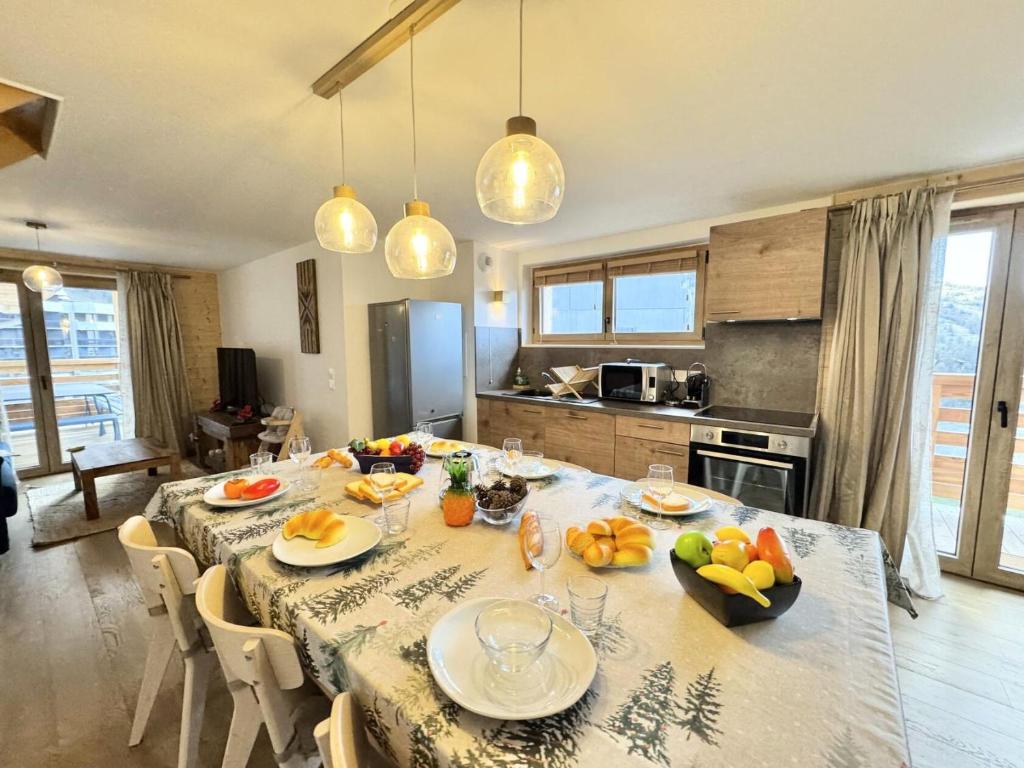 a kitchen with a table with plates and fruit on it at Résidence Le Living Stone B - LIVING STONE B MAE-1781 in Vars