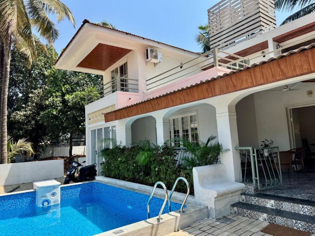 a house with a swimming pool in front of a house at Sun-kissed Holidays, Goa - Copper in Serula