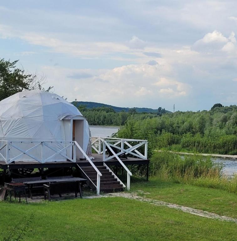 a yurt with a porch and stairs next to a river at Глемпінг Еко-сфера in Dubovtsy