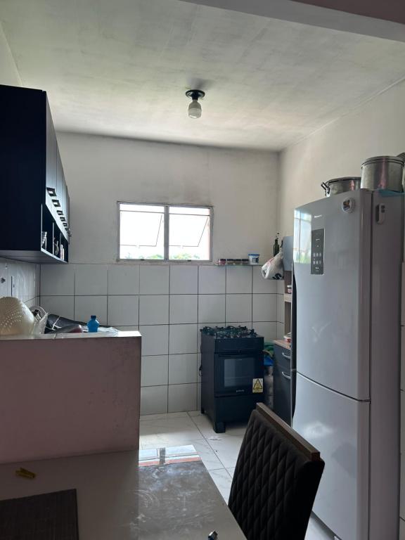 Una cocina con un refrigerador y una mesa dentro. en Residencial Juscelino Kubitscheck, en Ananindeua