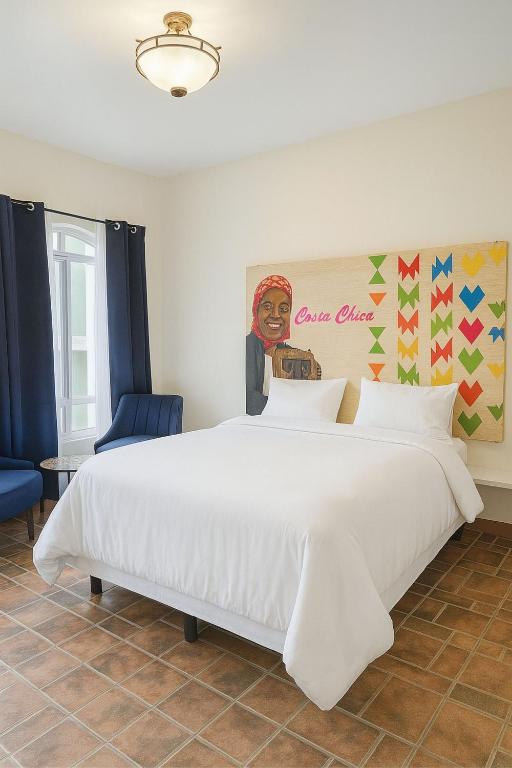 a large white bed in a room with a painting at Casa Xochitl in Oaxaca City
