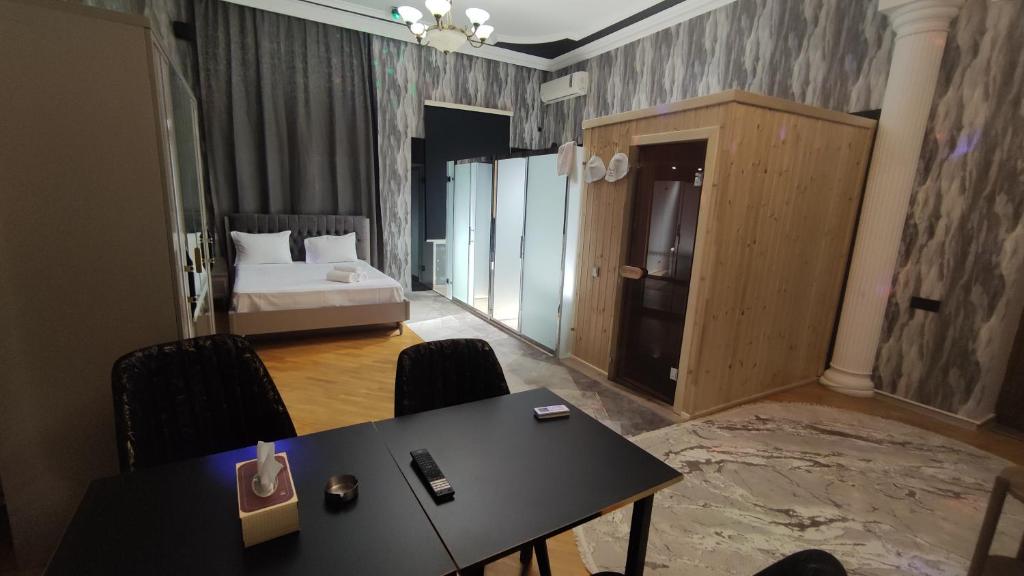 a room with a table and a bed and a bedroom at Hotel Badamdar Baku in Baku