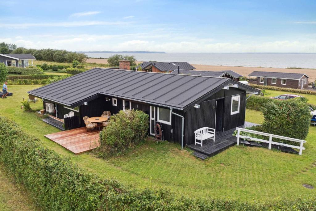 a black house with a deck and the ocean at Lovely Summerhouse By Skaastrup Strand W Sea View in Bogense