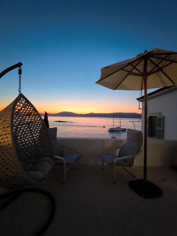 a patio with chairs and an umbrella and a table with a boat at "Villa Kanella"Sea View Hydra Kamini malouholidays in Hydra