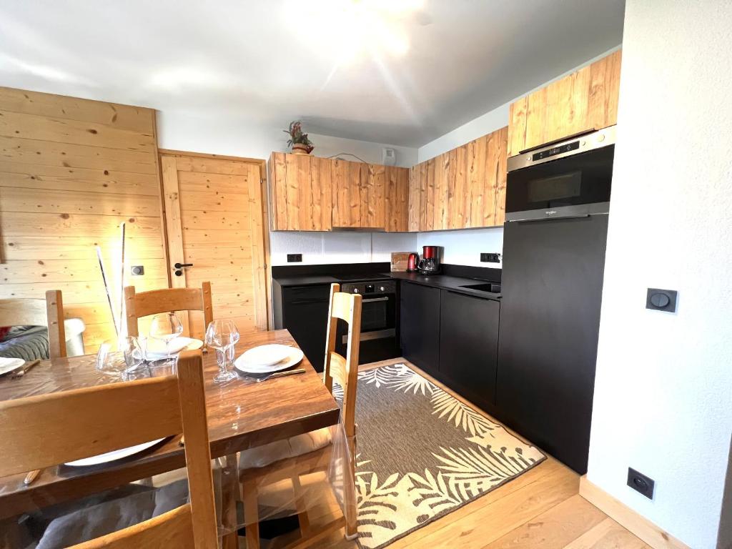 a kitchen with a table and a black refrigerator at Esprit chalet-Le Snoroc C36 in Aime La Plagne