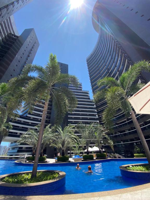 a pool with palm trees in front of buildings at Hotel Platinum - Landscape Luxo - in Fortaleza