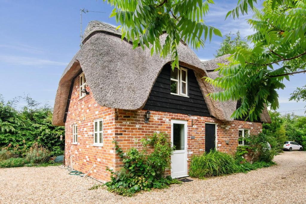 a small brick house with a thatched roof at Charming thatched cottage near New Forest in Breamore