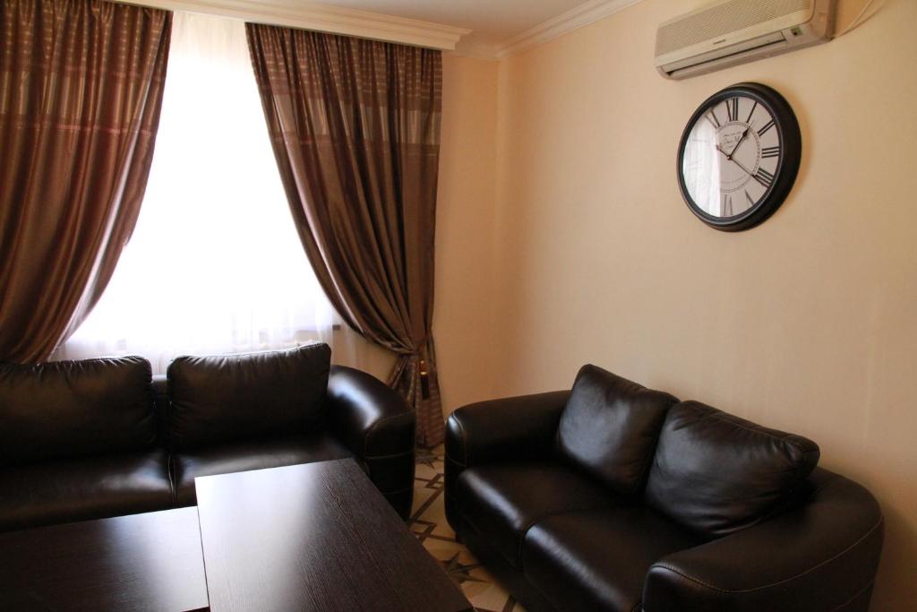 een woonkamer met een bank en een klok aan de muur bij Satti in Zharkent